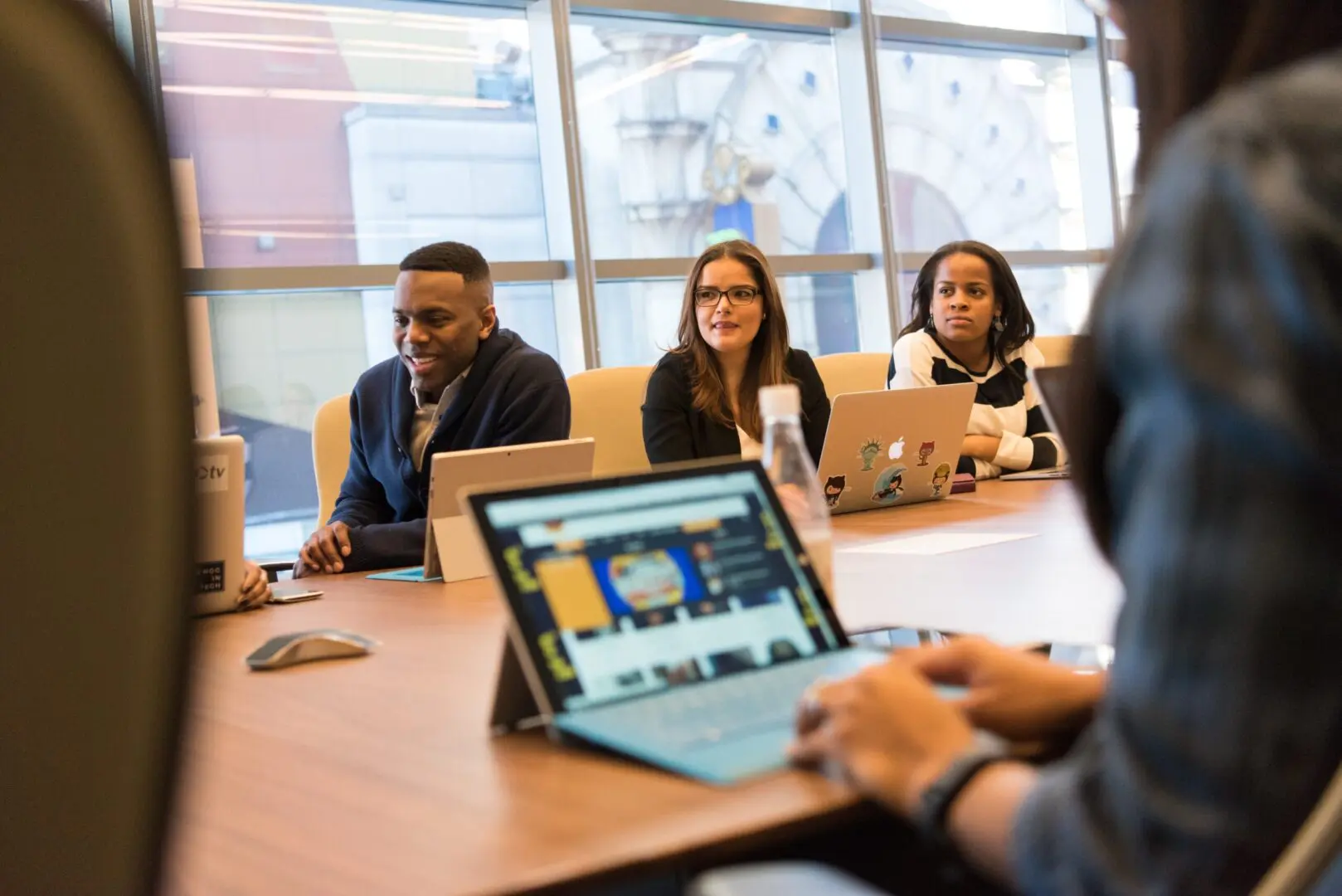 A group of people sitting around a table with laptops.